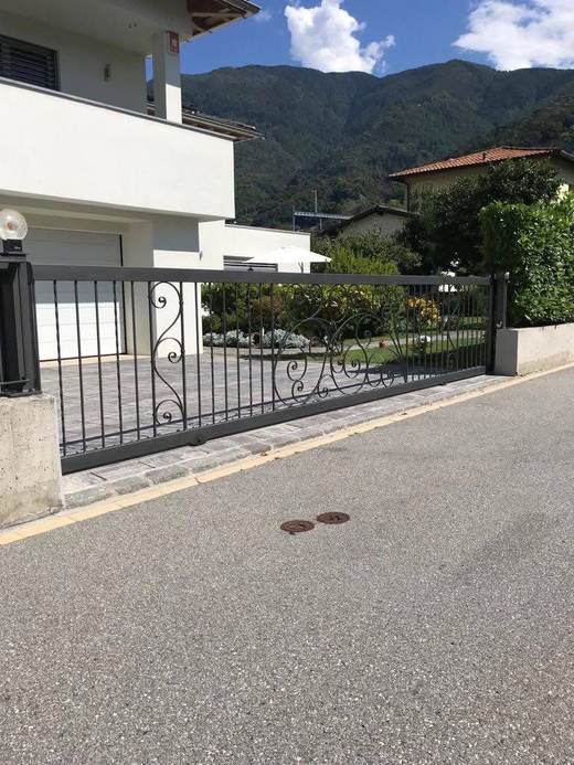 Cancello scorrevole in ferro battuto con decoro a riccioli, installato su villa privata