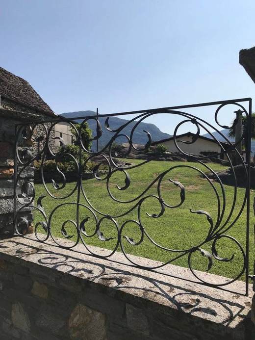Ringhiera decorativa in ferro battuto con motivo a foglie, su muretto in pietra
